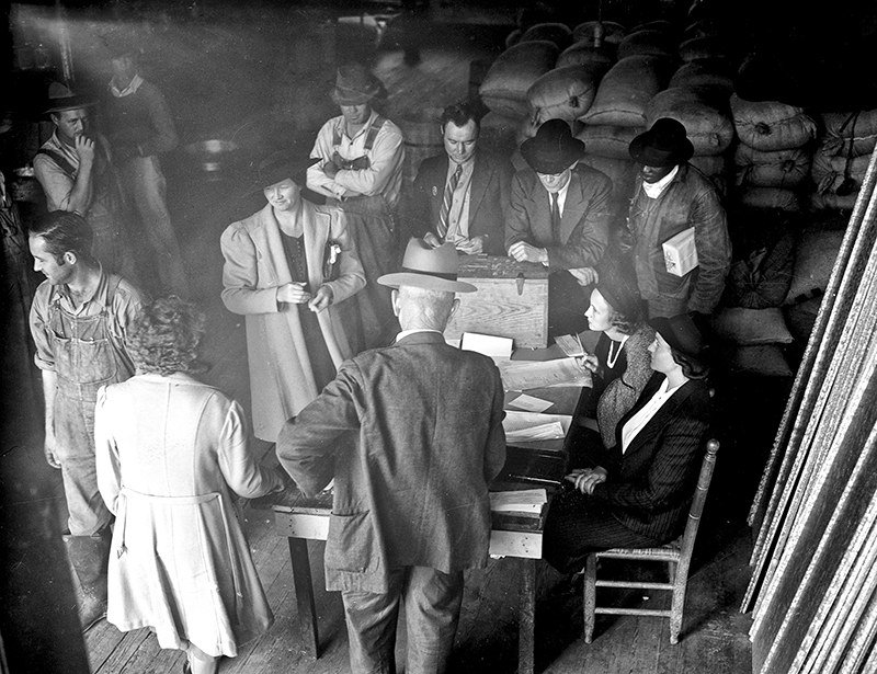 Farmers and townspeople crowd around a table to cast ballots inside Jackson Warehouse in Apex, about 1930