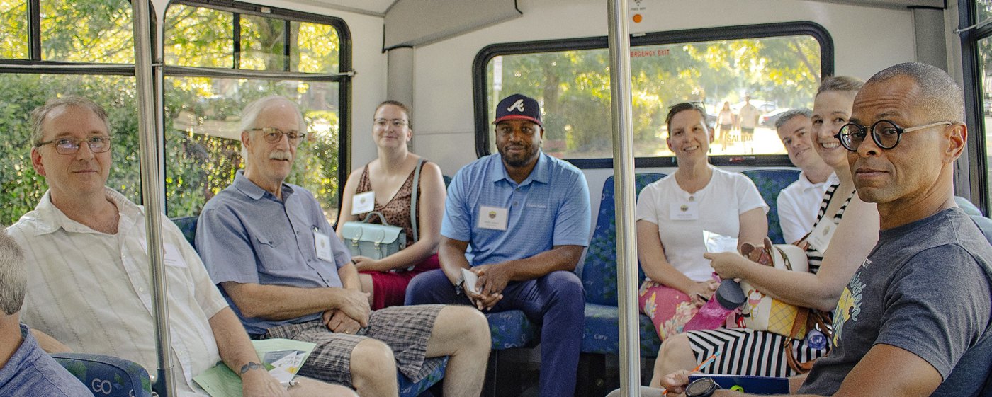 Adults seated inside a GoApex bus, smiling at the camera