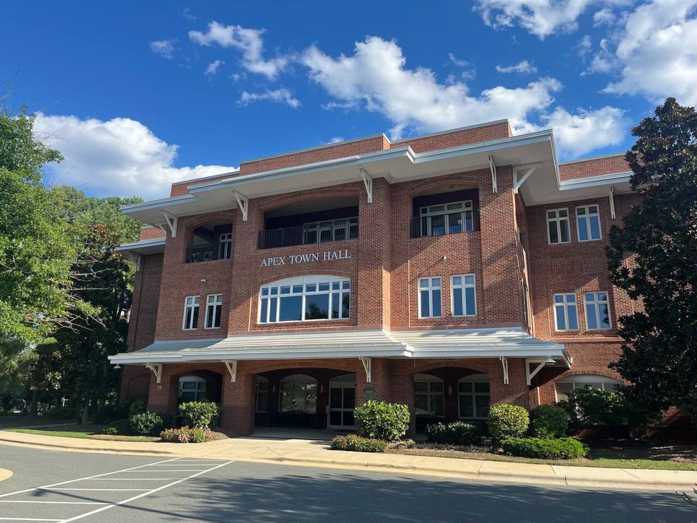 Apex Town Hall, a three-story brick building with white trim, under a blue sky