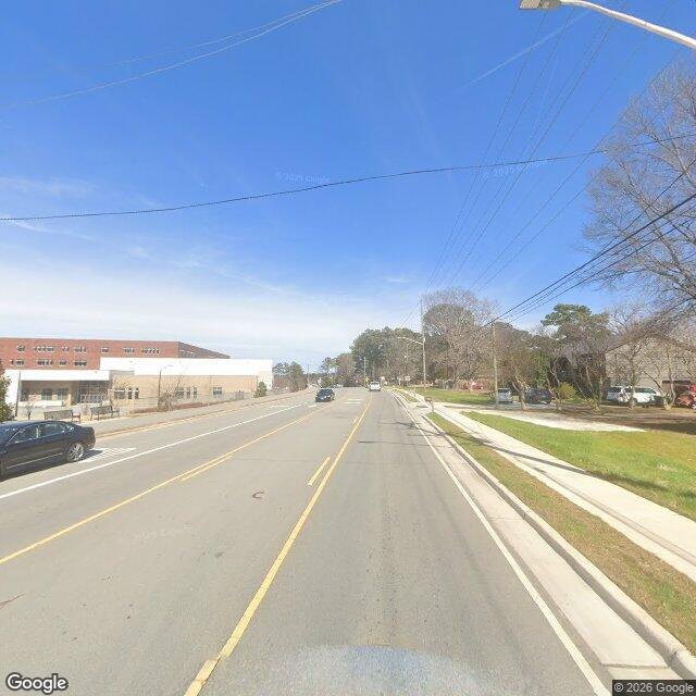 Street View of Laura Duncan Road looking north toward U.S. 64, with Apex High School's brick building on the left and a sidewalk on the right